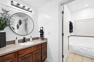 Full bathroom featuring a garden tub, light tile patterned floors, and vanity