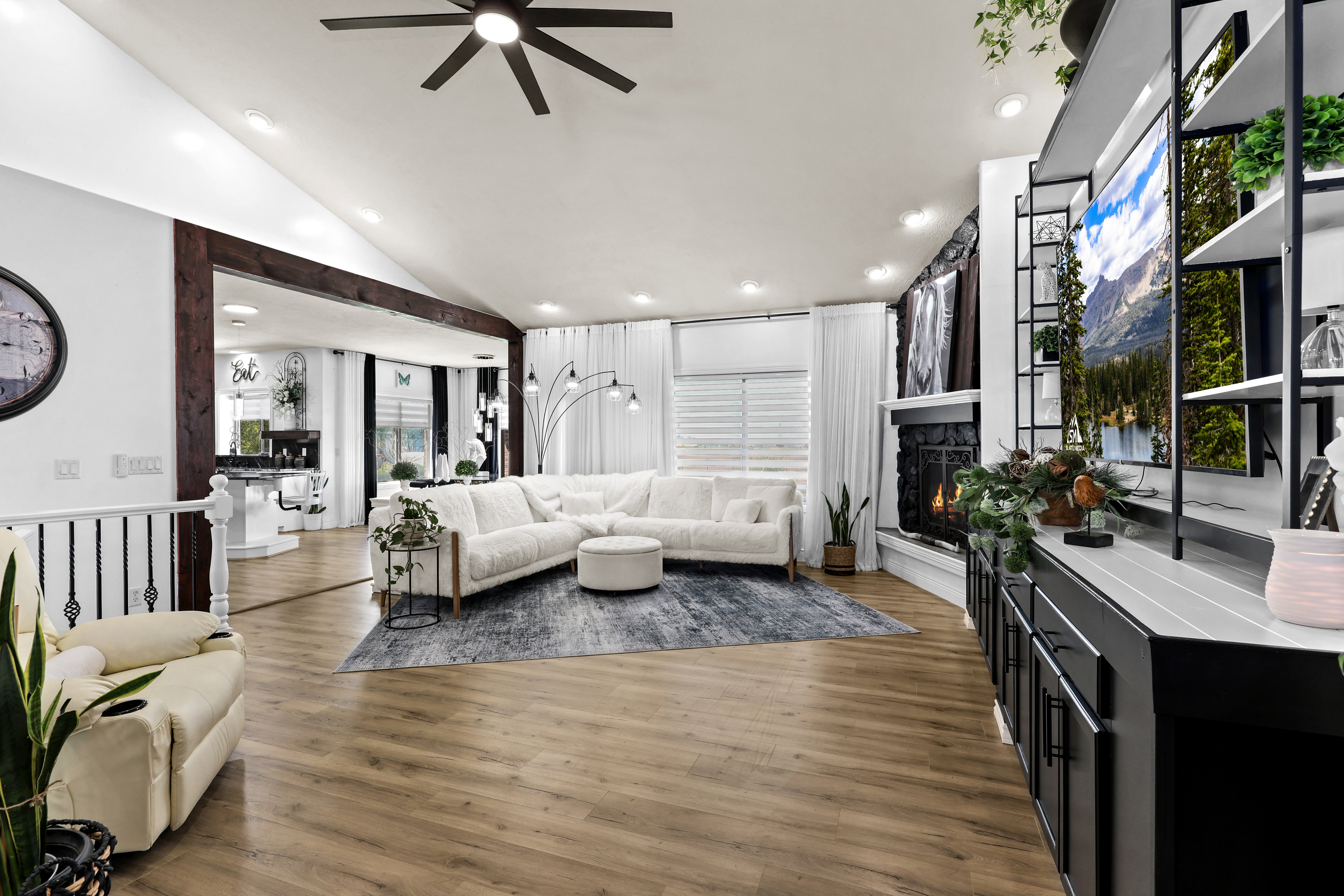 Living room featuring ceiling fan, dark wood-type flooring, lofted ceiling, a stone fireplace, and recessed lighting