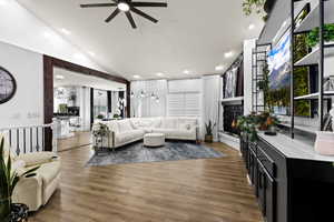 Living room featuring ceiling fan, dark wood-type flooring, lofted ceiling, a stone fireplace, and recessed lighting