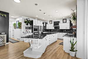 Kitchen with dark stone countertops, a center island, white cabinets, a kitchen bar, and tasteful backsplash