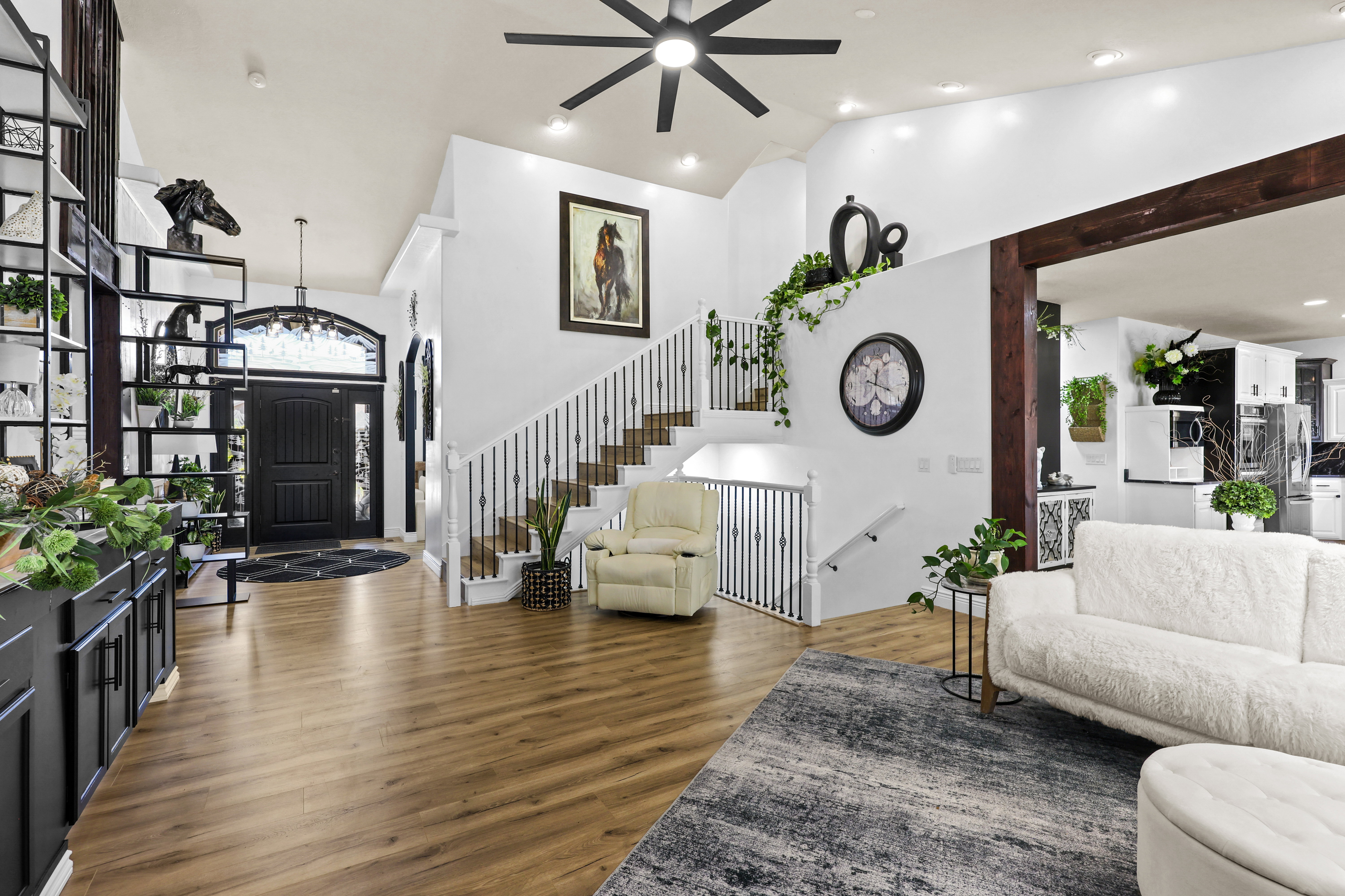 Living area featuring dark wood finished floors, vaulted ceiling, a chandelier, and ceiling fan