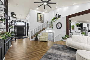 Living area featuring dark wood finished floors, vaulted ceiling, a chandelier, and ceiling fan
