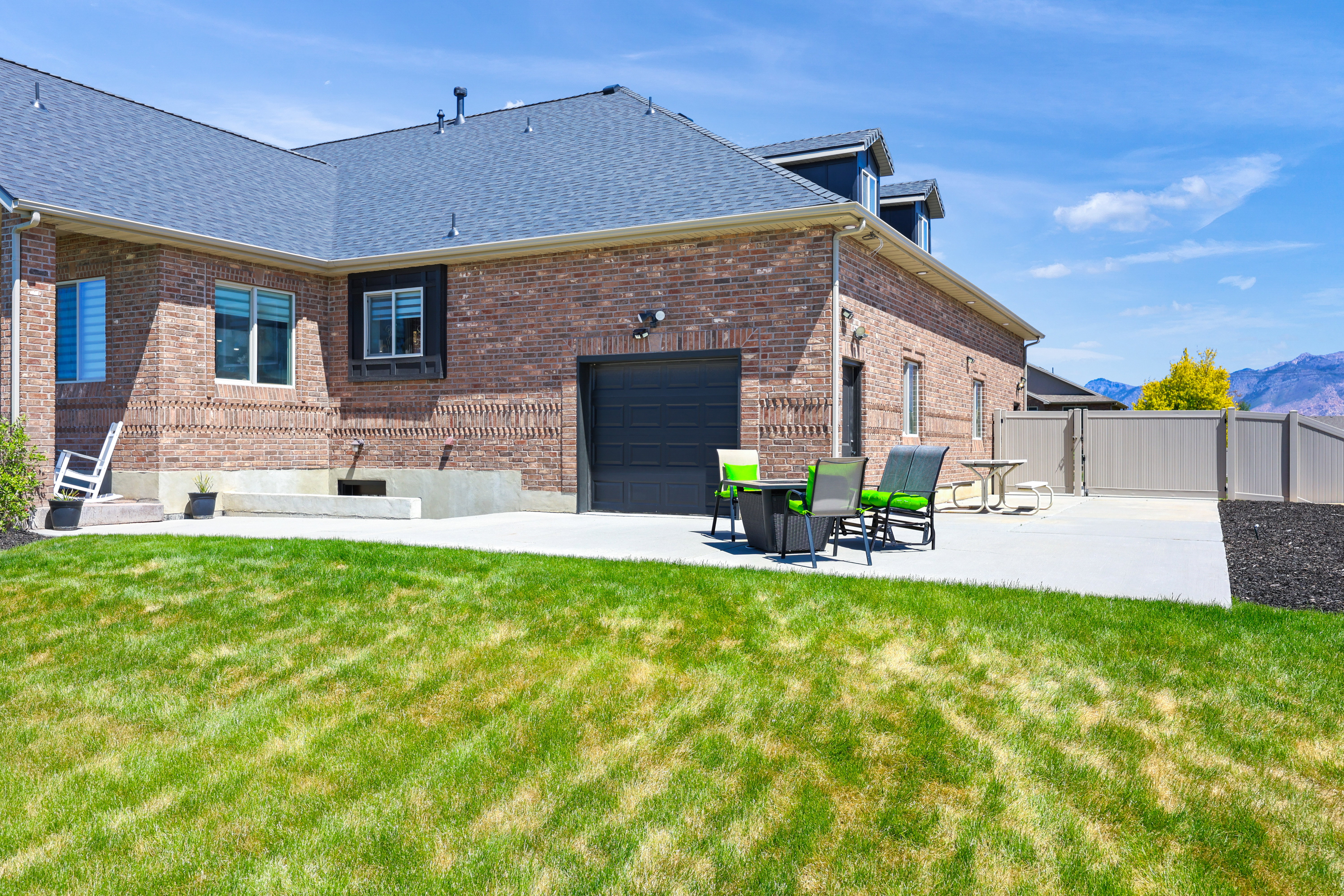 Rear view of property with brick siding, a patio, a shingled roof, a mountain view, and a gate