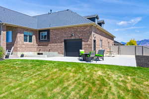 Rear view of property with brick siding, a patio, a shingled roof, a mountain view, and a gate