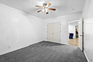 Unfurnished bedroom featuring carpet flooring, a ceiling fan, and a closet