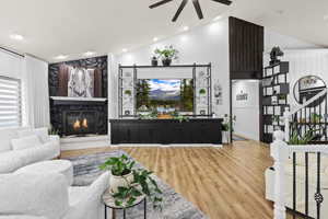 Living area with lofted ceiling, light wood finished floors, a ceiling fan, a fireplace, and recessed lighting