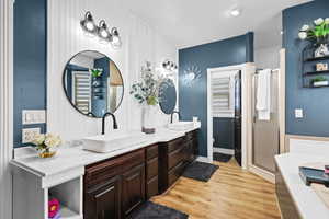 Bathroom with double vanity, a stall shower, light wood finished floors, and a bath