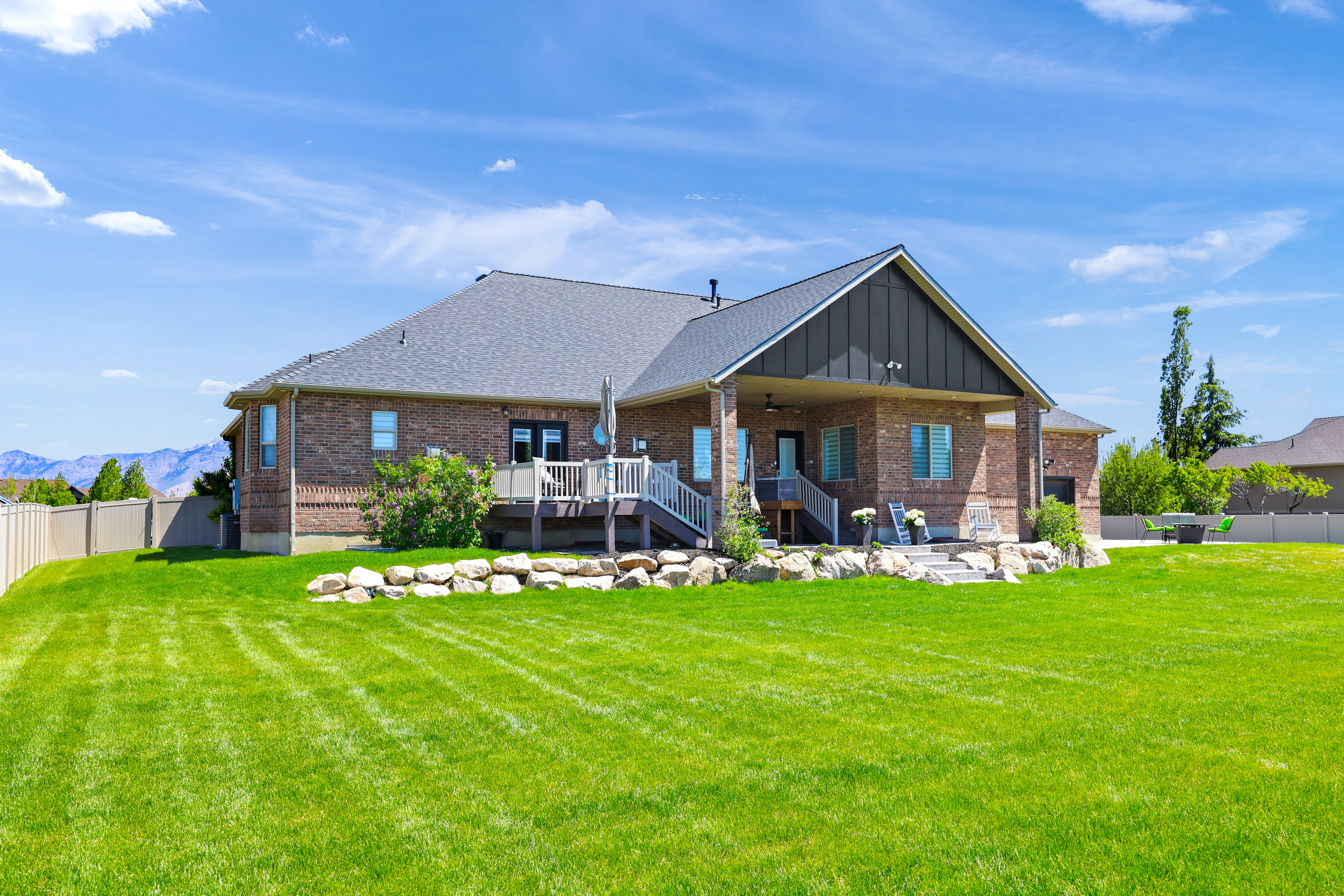 Rear view of house with a fenced backyard, brick siding, a ceiling fan, board and batten siding, and a patio area
