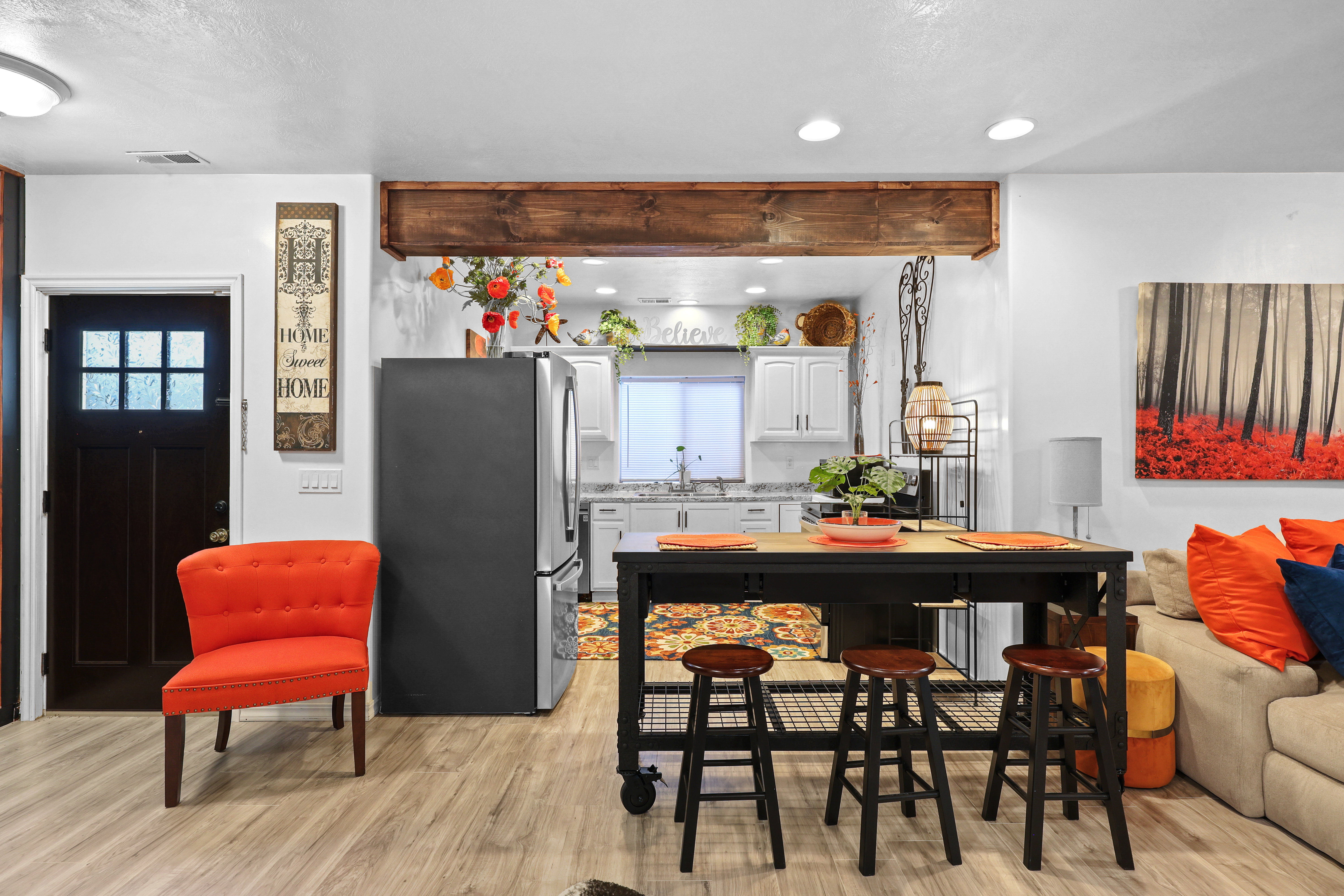 Kitchen with freestanding refrigerator, white cabinetry, a breakfast bar, light wood-style floors, and recessed lighting