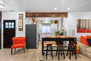 Kitchen with freestanding refrigerator, white cabinetry, a breakfast bar, light wood-style floors, and recessed lighting