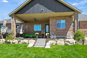 Rear view of house featuring a yard, a ceiling fan, brick siding, and an outdoor living space