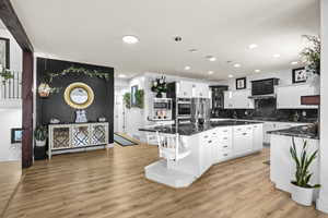Kitchen featuring hanging light fixtures, dark stone countertops, a kitchen island, and white cabinetry