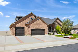 View of front facade with a gate, brick siding, a garage, and driveway