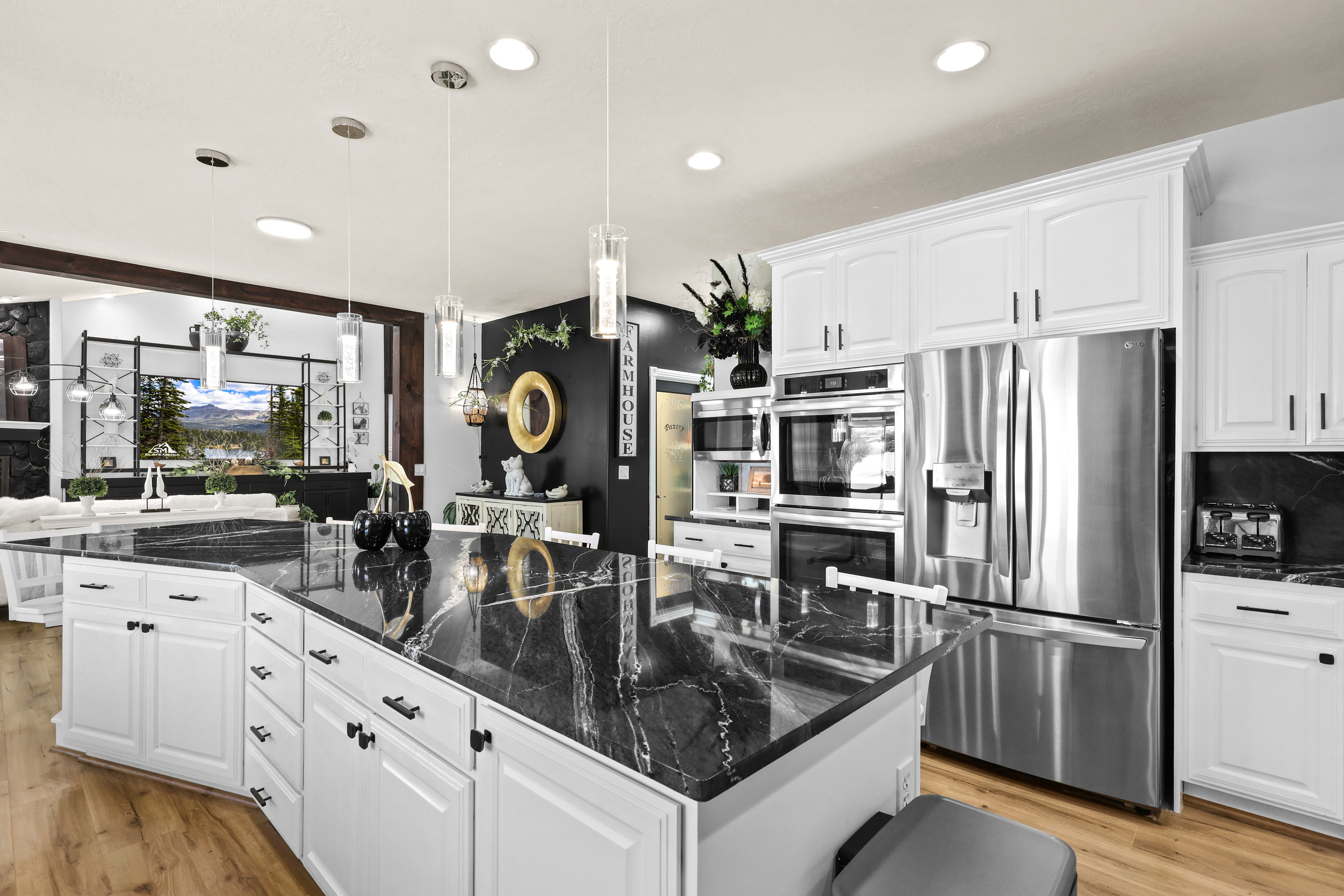 Kitchen with white cabinets, stainless steel appliances, dark stone counters, decorative light fixtures, and light wood-style flooring