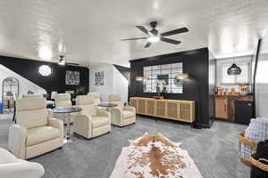 Carpeted home theater with a textured ceiling and a ceiling fan