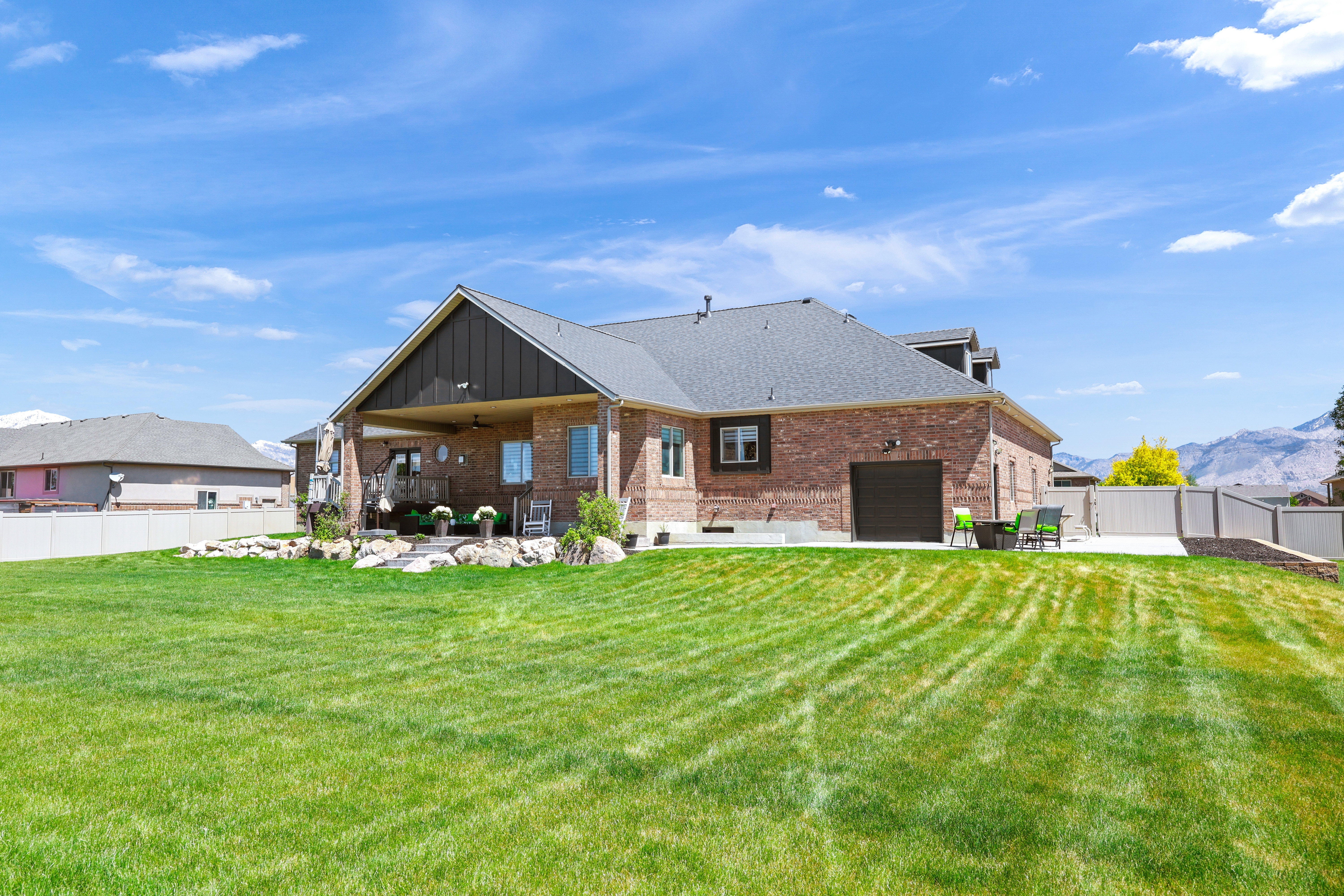 Back of property with a fenced backyard, brick siding, a ceiling fan, a patio area, and a mountain view