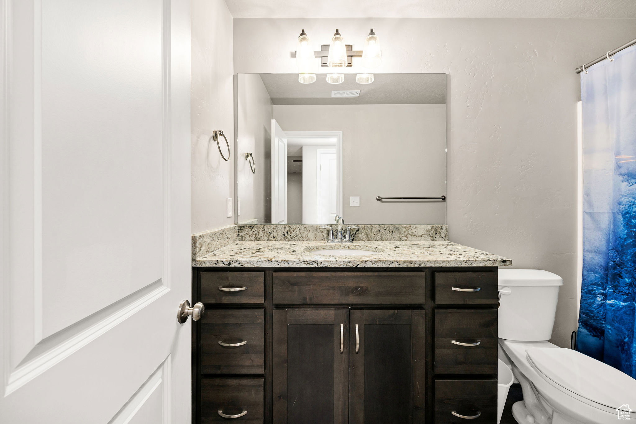 Full bath featuring vanity, curtained shower, and a textured wall