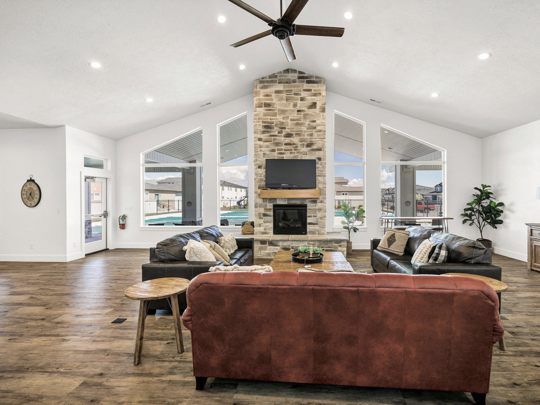 Living area featuring a fireplace, dark wood-type flooring, recessed lighting, a ceiling fan, and a high ceiling