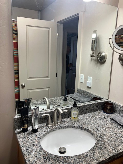 Vanity featuring a built-in oval sink, speckled countertop, and brushed nickel faucet