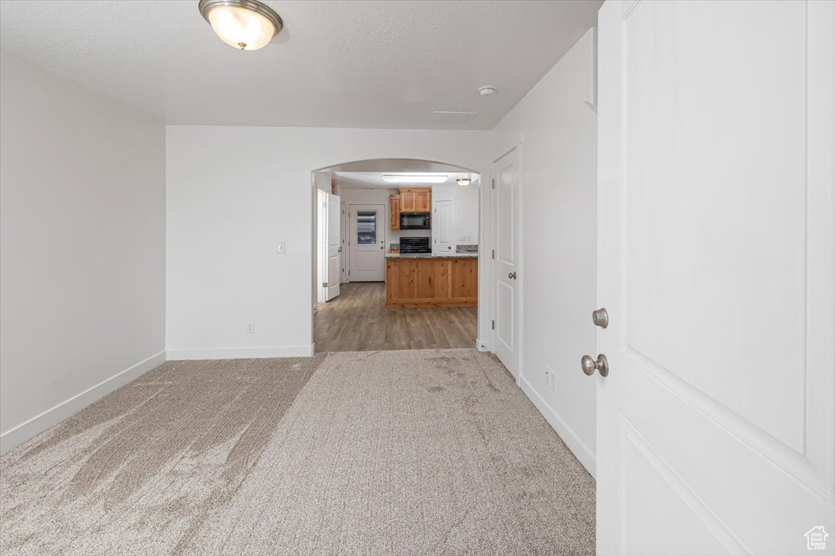 Unfurnished room with arched walkways and light colored carpet
