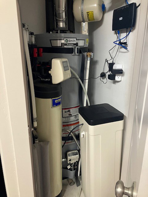 Utility closet with a water heater, water softener system, and water filtration system