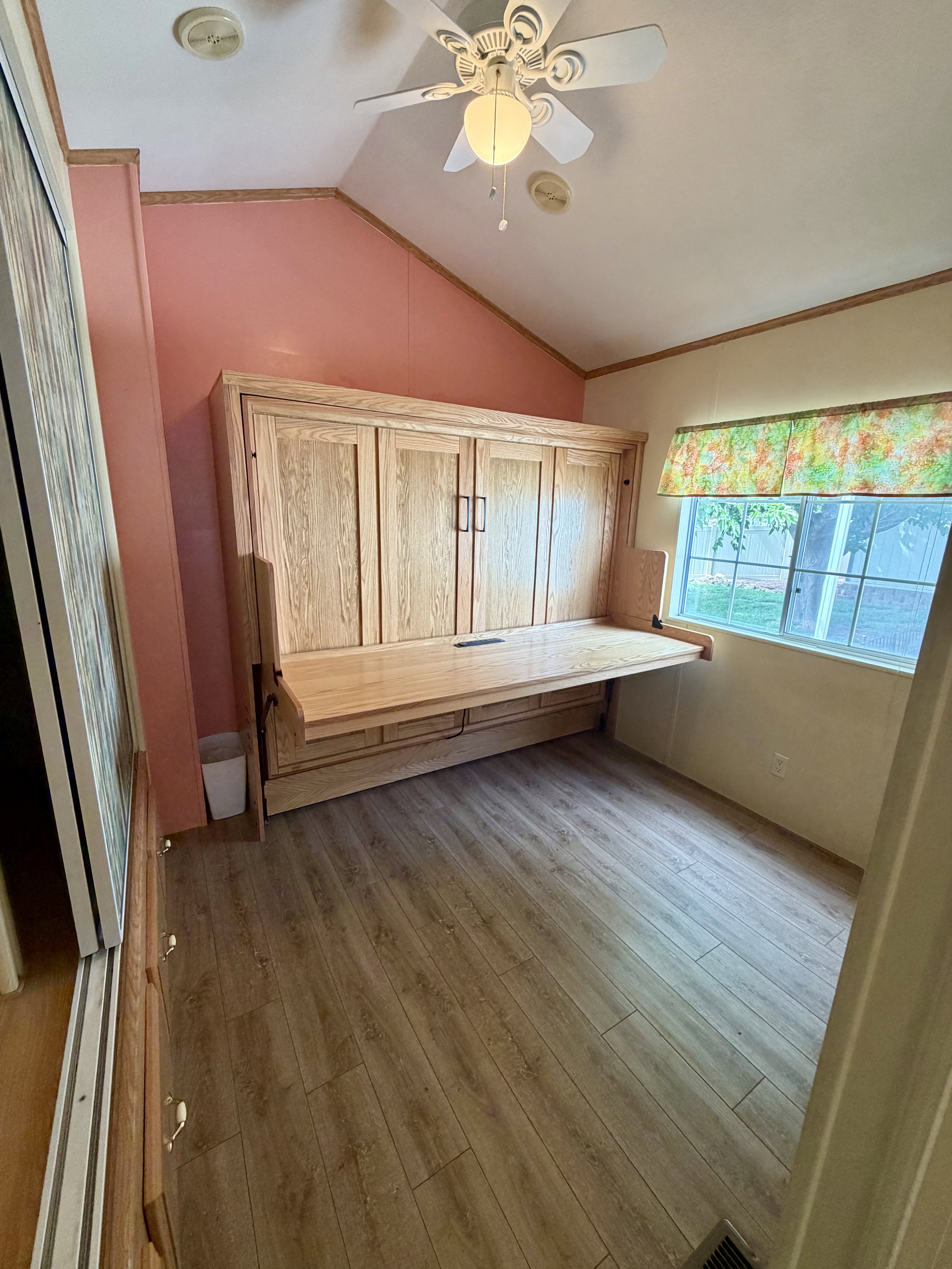 Unfurnished office featuring vaulted ceiling, a ceiling fan, light wood-style flooring, and ornamental molding