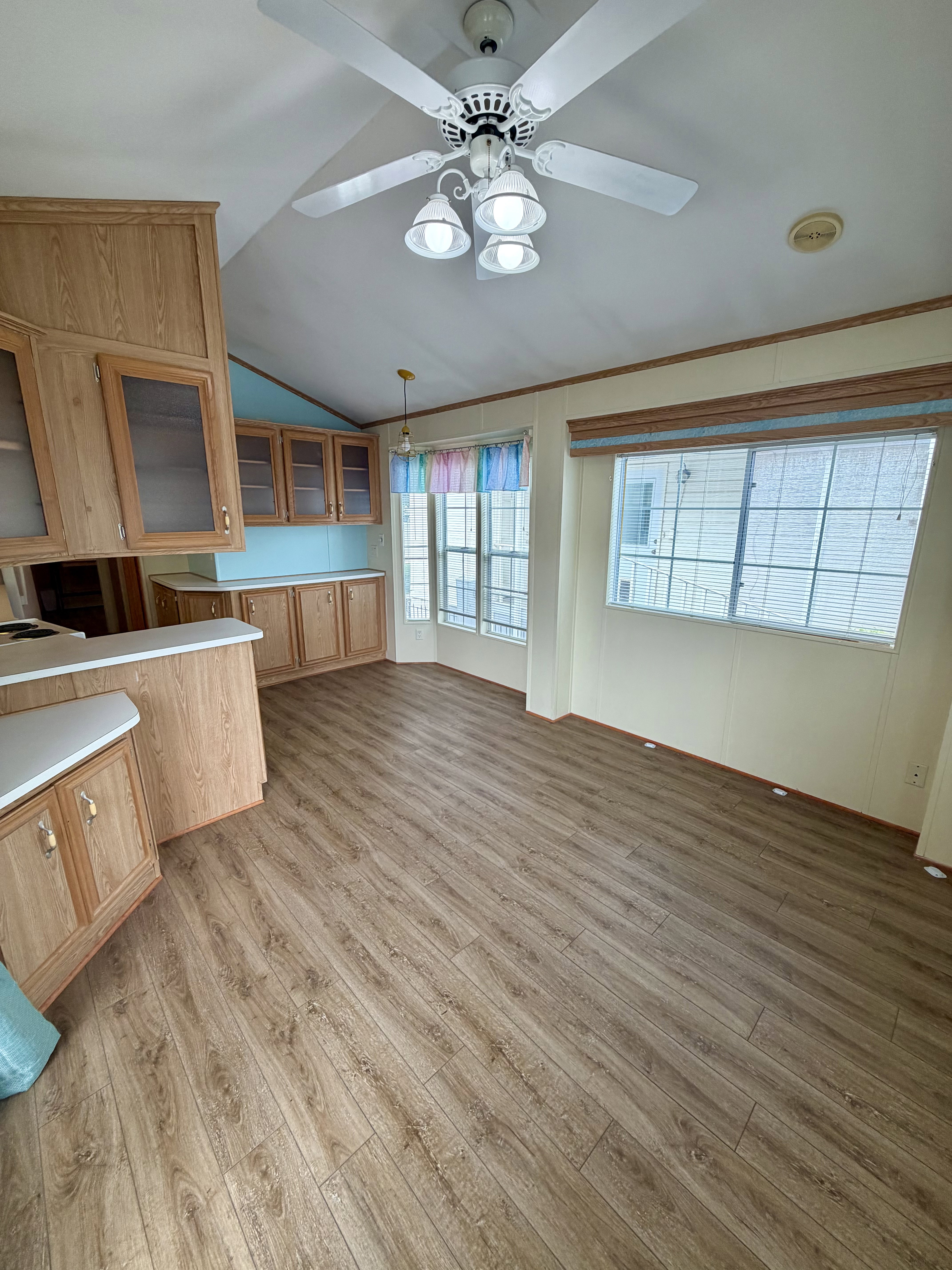 Kitchen featuring glass fronted cabinets, light wood finished floors, light countertops, vaulted ceiling, and hanging light fixtures