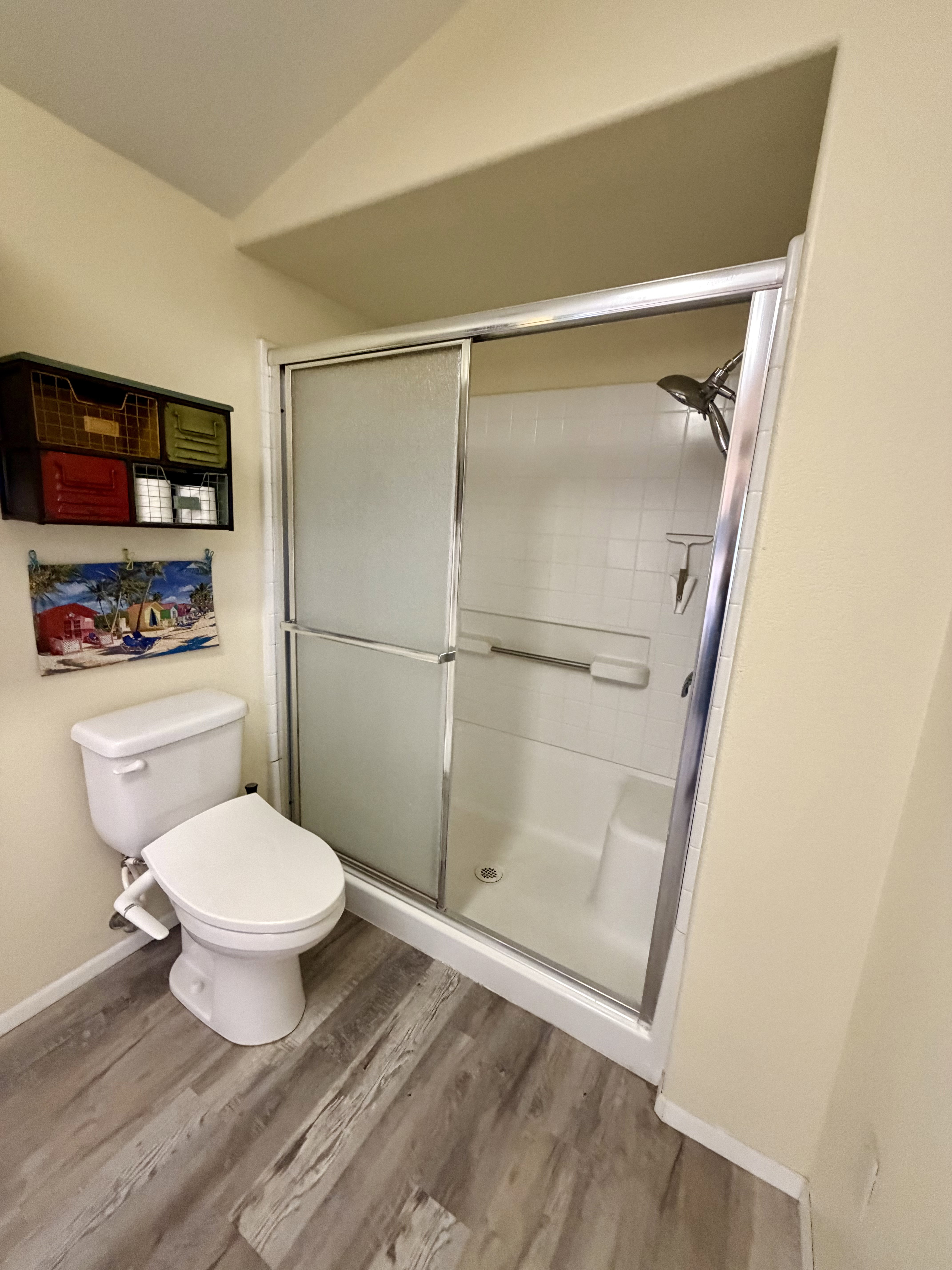 Full bath featuring a stall shower, vaulted ceiling, and light wood-style floors