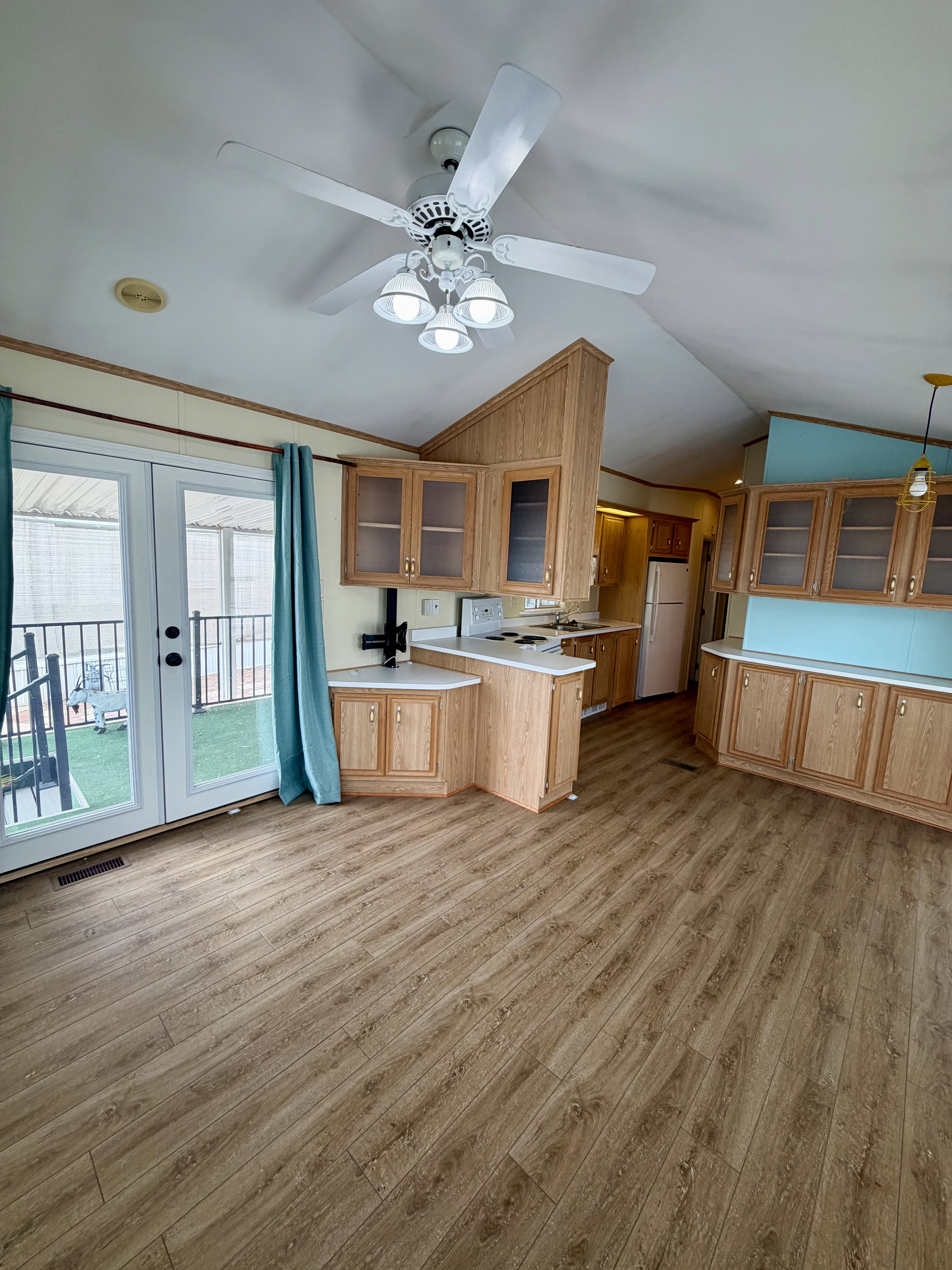 Kitchen with glass fronted cabinets, a peninsula, light countertops, light wood-type flooring, and lofted ceiling