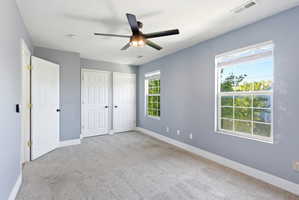 Unfurnished bedroom featuring two closets, light carpet, and a ceiling fan