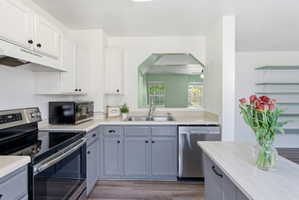 Kitchen with stainless steel appliances, dual tone cabinetry, and light wood-type flooring
