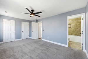 Unfurnished bedroom with two closets, light colored carpet, ensuite bathroom, and ceiling fan