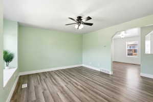 Spare room with a ceiling fan, wood finished floors, and arched walkways