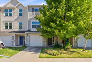 View of front of home featuring concrete driveway, a front lawn, and an attached garage