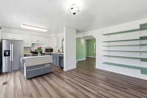 Dual tone kitchen featuring light countertops, stainless steel appliances, light wood-style floors, two tone cabinets, and a kitchen island