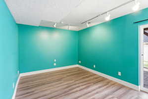 Spare room with rail lighting and light wood-style flooring