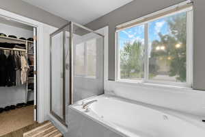 Bathroom featuring a spacious closet, a shower stall, and a bath