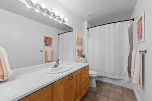 Full bathroom featuring vanity, shower / tub combo with curtain, and stone finish flooring
