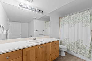 Bathroom with vanity, a textured ceiling, wood finished floors, and shower / bath combination with curtain