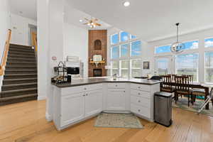 Kitchen featuring open floor plan, white cabinetry, light wood finished floors, and a high ceiling
