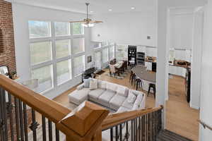 Living room featuring a high ceiling, a ceiling fan, light wood-style floors, and recessed lighting