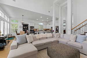 Living area with a chandelier, healthy amount of natural light, a high ceiling, and light wood finished floors