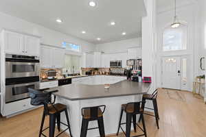Kitchen featuring a kitchen bar, white cabinets, decorative backsplash, black appliances, and a high ceiling