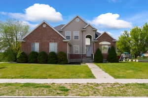 Traditional home with a front lawn, stucco siding, and brick siding