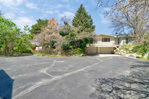 View of parking featuring an attached garage and asphalt driveway