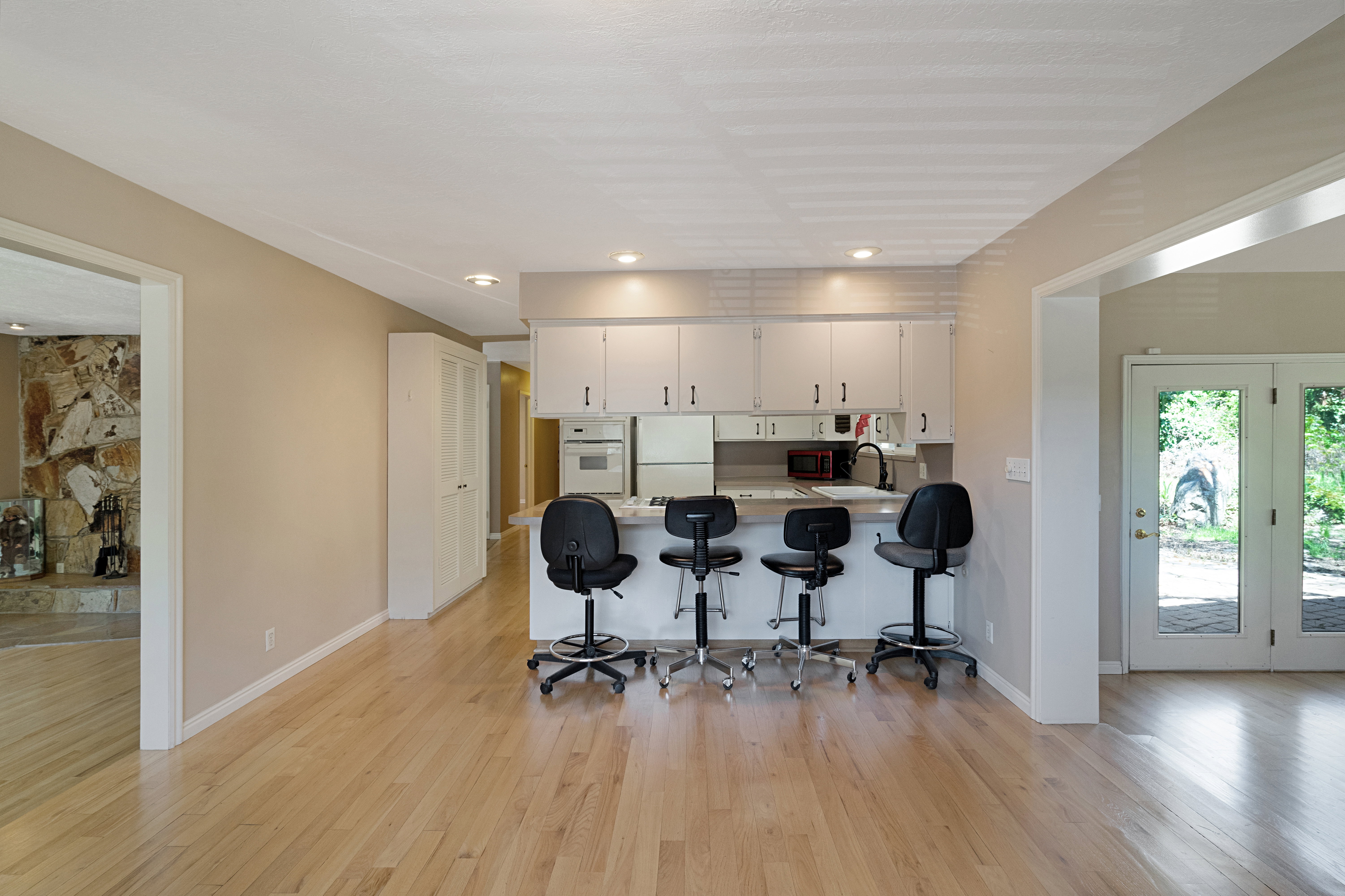 Kitchen featuring a peninsula, a breakfast bar, light countertops, light wood finished floors, and white appliances