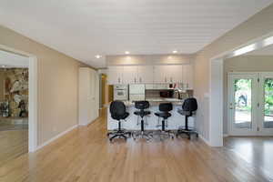 Kitchen featuring a peninsula, a breakfast bar, light countertops, light wood finished floors, and white appliances