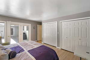 Bedroom with multiple closets and light wood-style floors