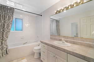 Bathroom with tiled shower / bath combo, vanity, and light tile patterned flooring