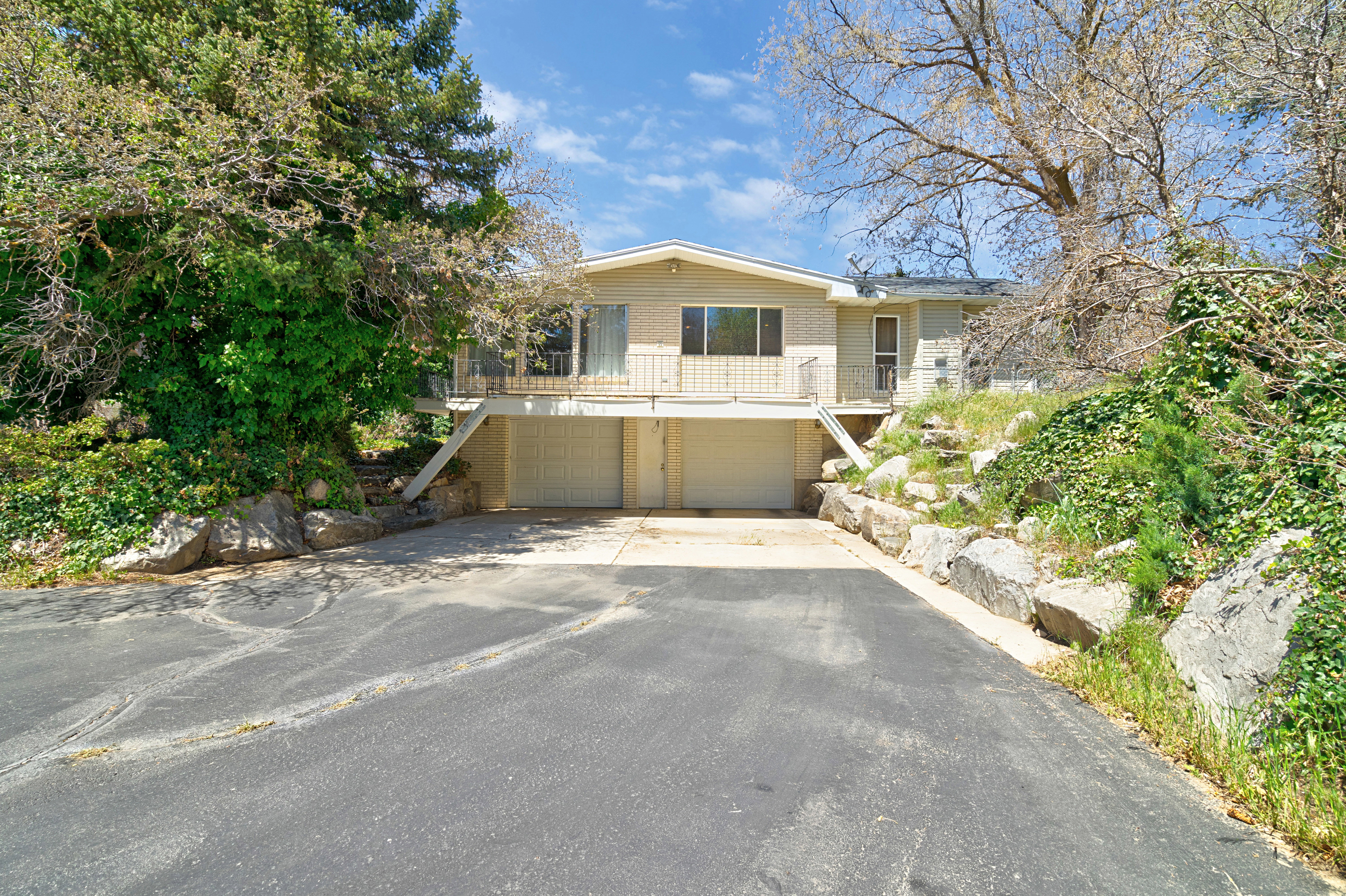 View of front of property featuring asphalt driveway, a garage, a balcony, and brick siding